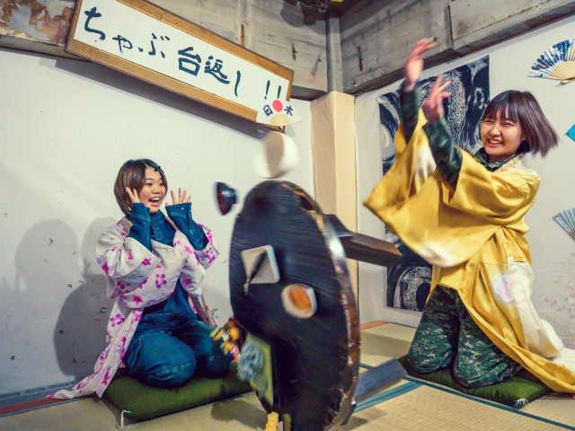 女性二人がちゃぶ台返しをしてスカッと楽しんでる様子