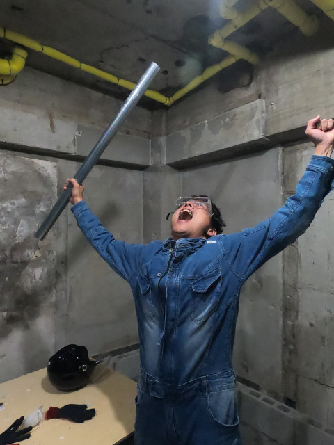 男性が鉄パイプを持ち大きく手を広げて雄たけびを上げている