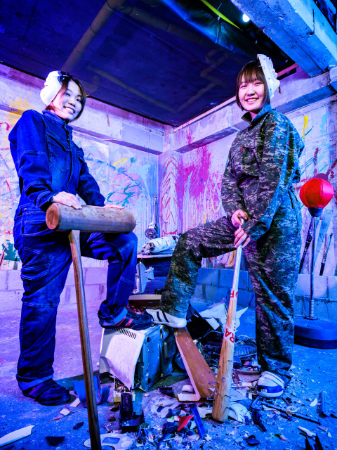 プレイルーム（破壊部屋）で女性二人が武器（餅つき杵とバット）で物を破壊尽くして、決めポーズ