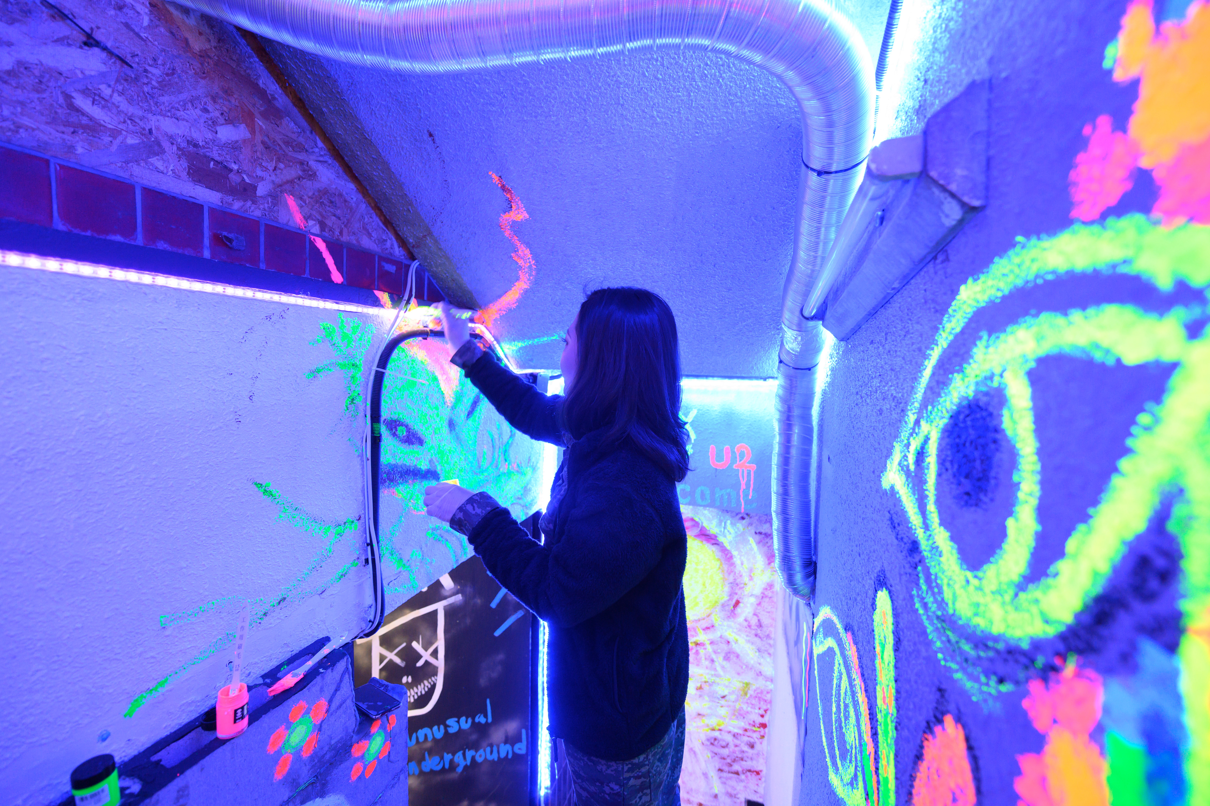 関西最大級のストレス発散アミューズメントU2で女性がU2の入り口の階段に絵を書いてる